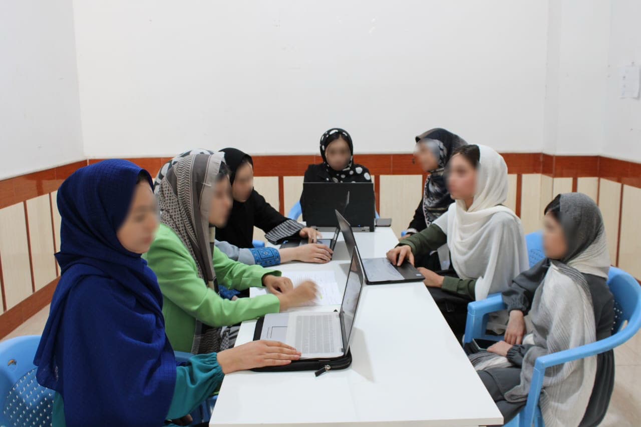 Afghan Girls Tech Academy students working together on laptops