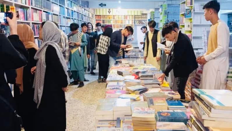 Afghan youth browsing books in a bookstore during a book access campaign